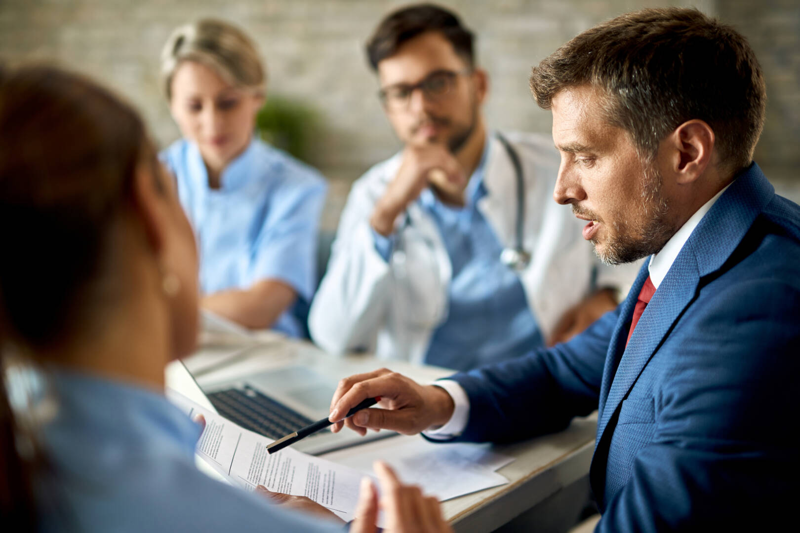 Businessman cooperating with doctors while going through reports on a meeting.