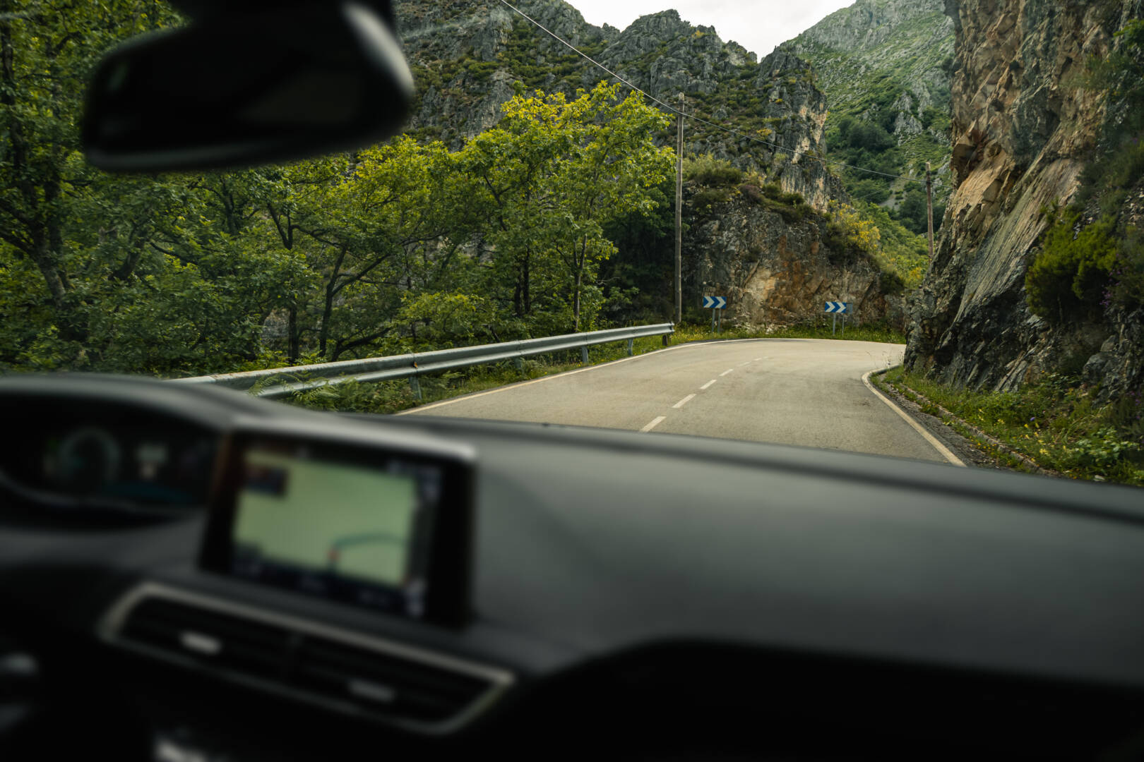 View of a road between the mountains through the windshield